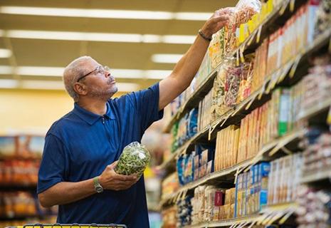 A man reaches for the top shelf in a grocery store